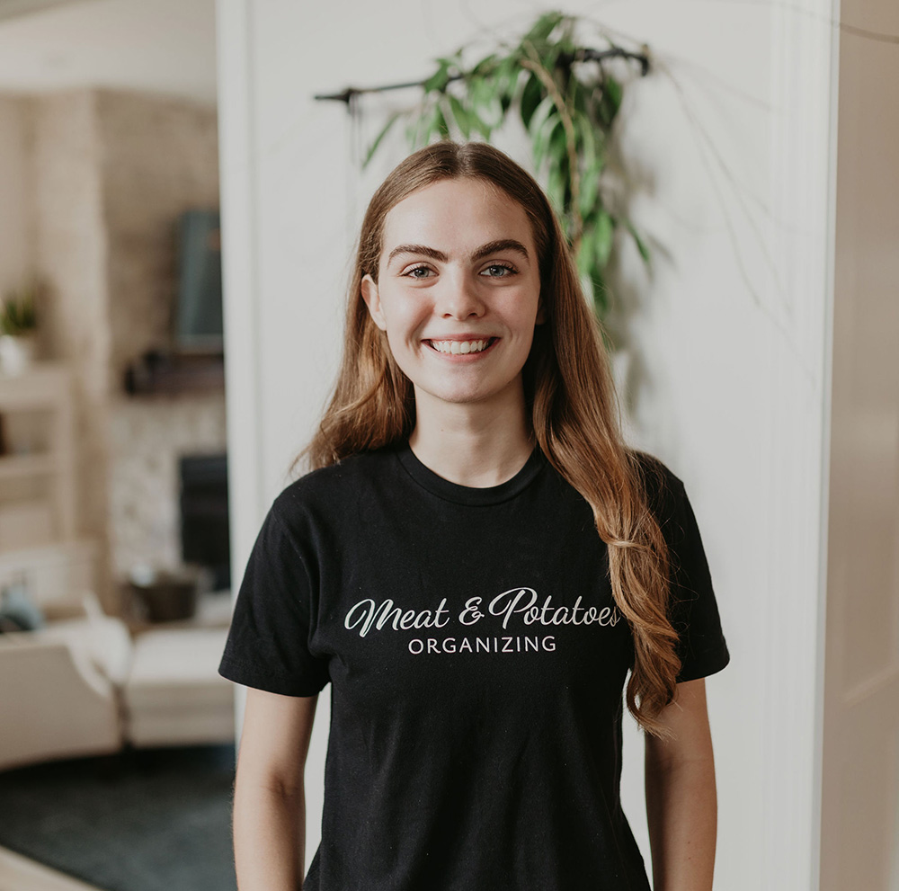 Olivia Link, a professional organizer, arranging items in a well-organized space in Saint Paul. Specializing in decluttering, space optimization, and creating functional organization systems for homes and businesses.