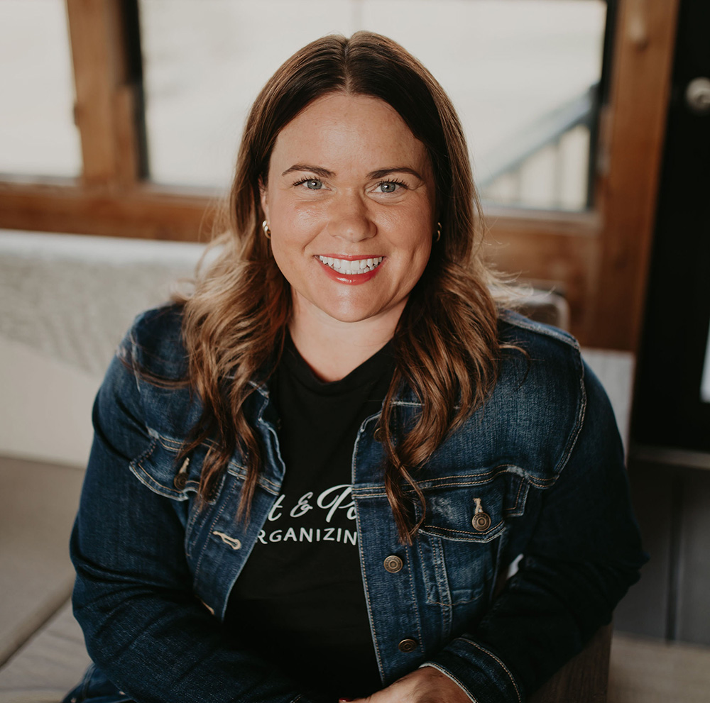 Cori McDougald, owner and lead professional organizer of Meat and Potatoes Organizing, smiling in a well-organized workspace. Specializing in organizing, relocation services, packing, and unpacking for homes and businesses in Edina, Minneapolis, and Saint Paul.